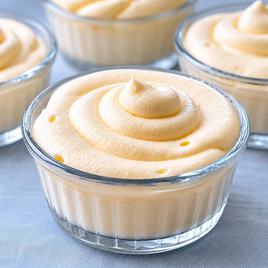 Fluffy lemon mousse in elegant glasses, drizzled with lemon curd and fresh mint