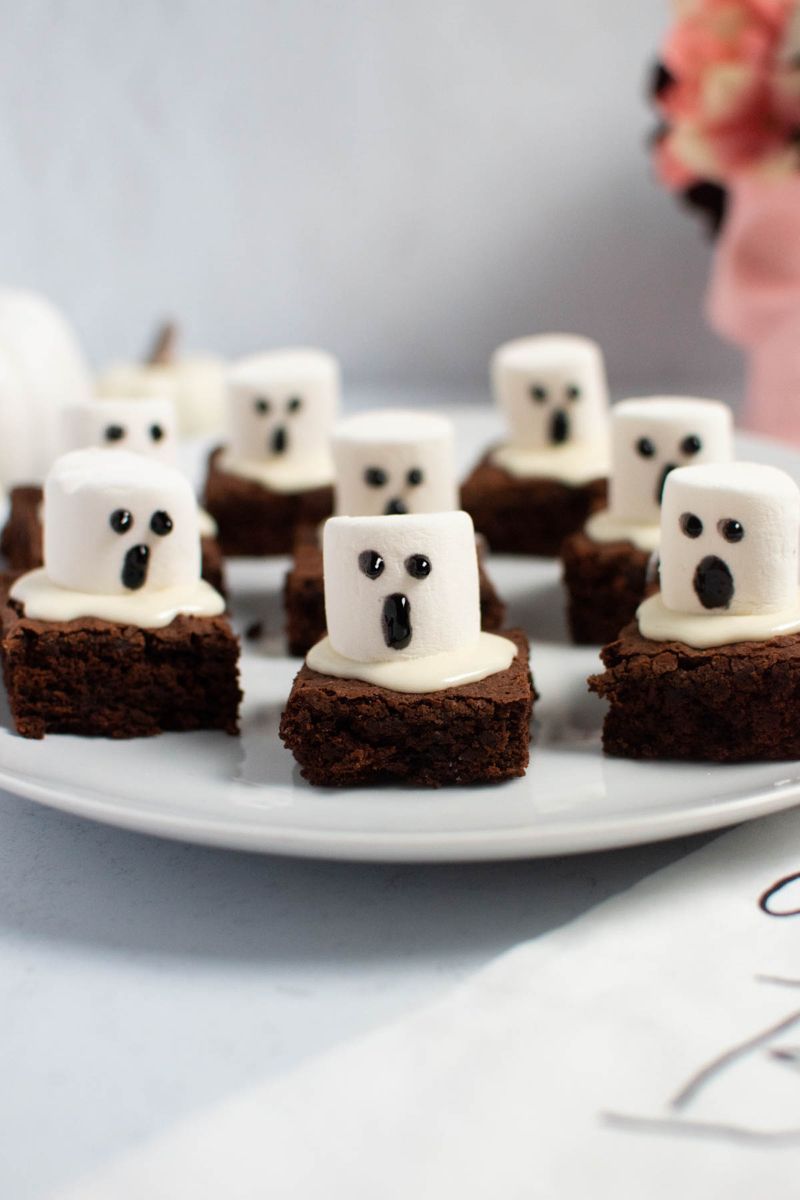 Fudgy chocolate brownies topped with white marshmallow “ghosts” and chocolate drizzle eyes.