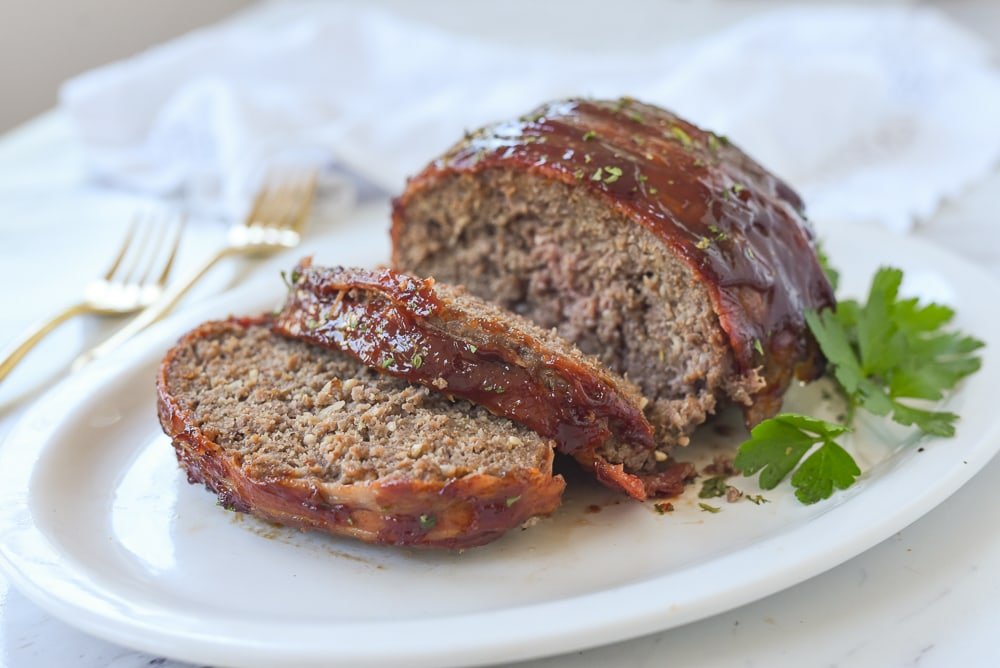 Smoky bacon-wrapped meatloaf with golden glaze, juicy beef center and crisp bacon edges