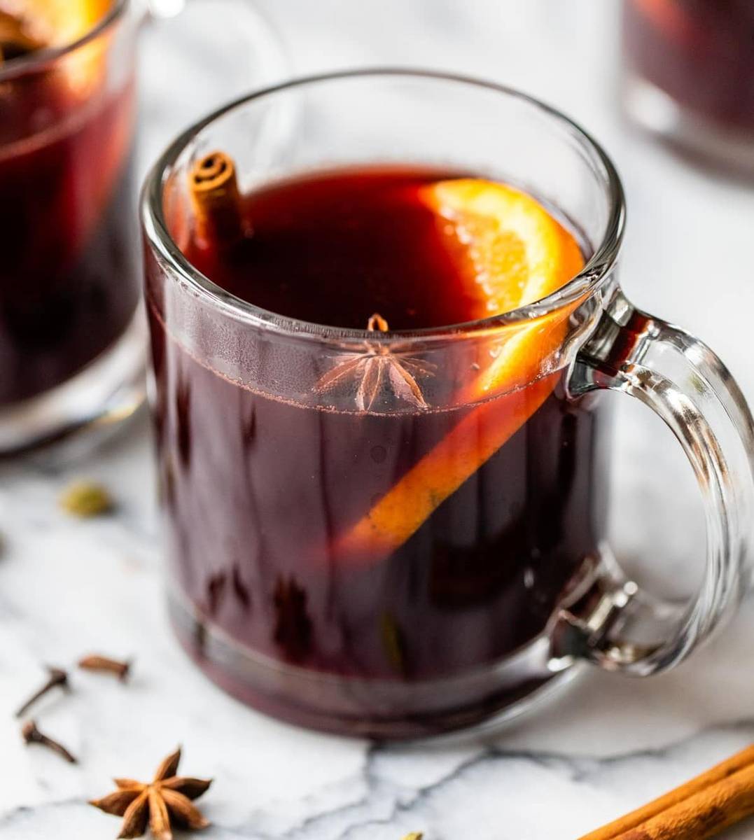 Slow cooker spiced red wine bubbling gently with apple slices, orange wheels, and cinnamon sticks