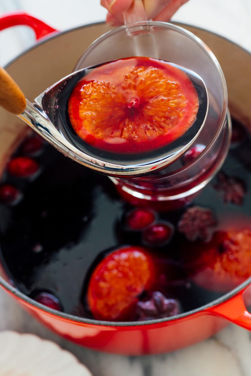 Classic red mulled wine with vibrant blood orange slices, cinnamon sticks, and whole cloves in mug