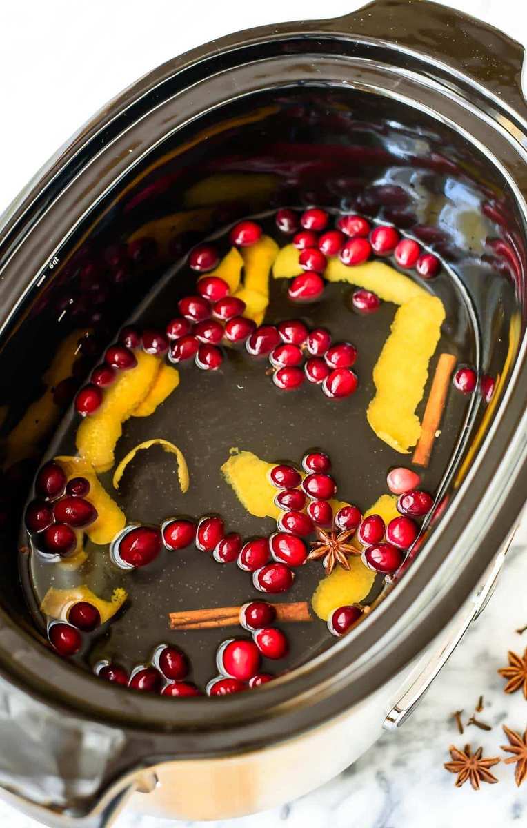 Golden mulled white wine infused with plump raisins, orange slices, and cinnamon in clear mugs.
