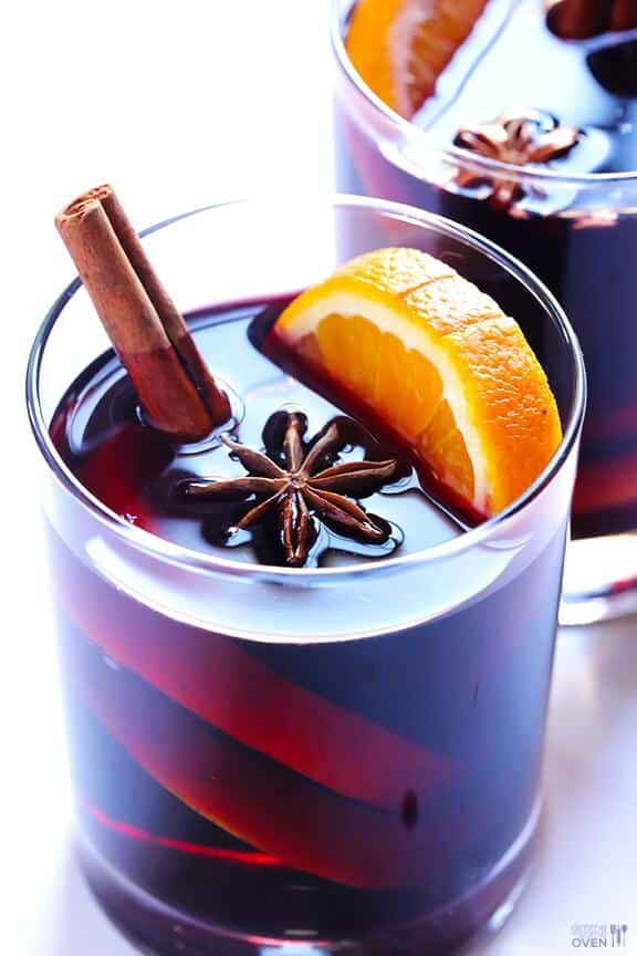 Vanilla bean mulled white wine with bright citrus wheels, whole cinnamon, and star anise in glass mugs.