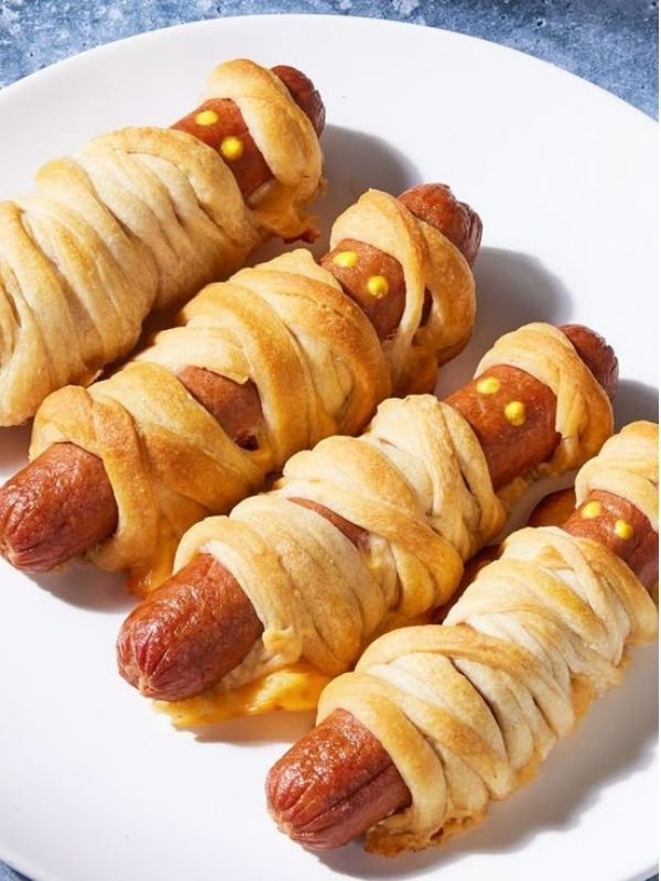 Full size hot dogs wrapped in thin ribbons of golden brown crescent dough with mustard eyes.