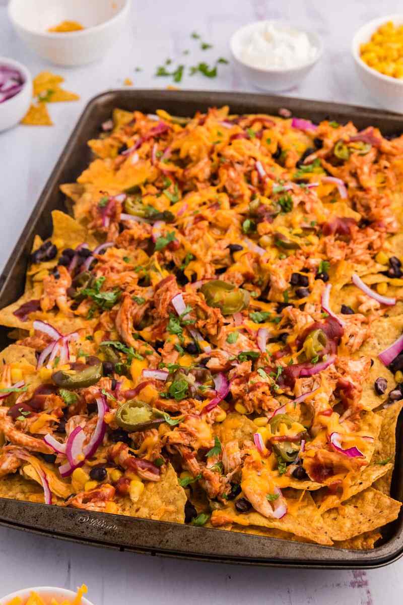 Bacon bourbon BBQ chicken nachos with melted cheddar cheese, smoky bacon, jalapeños, and crunchy tortilla chips