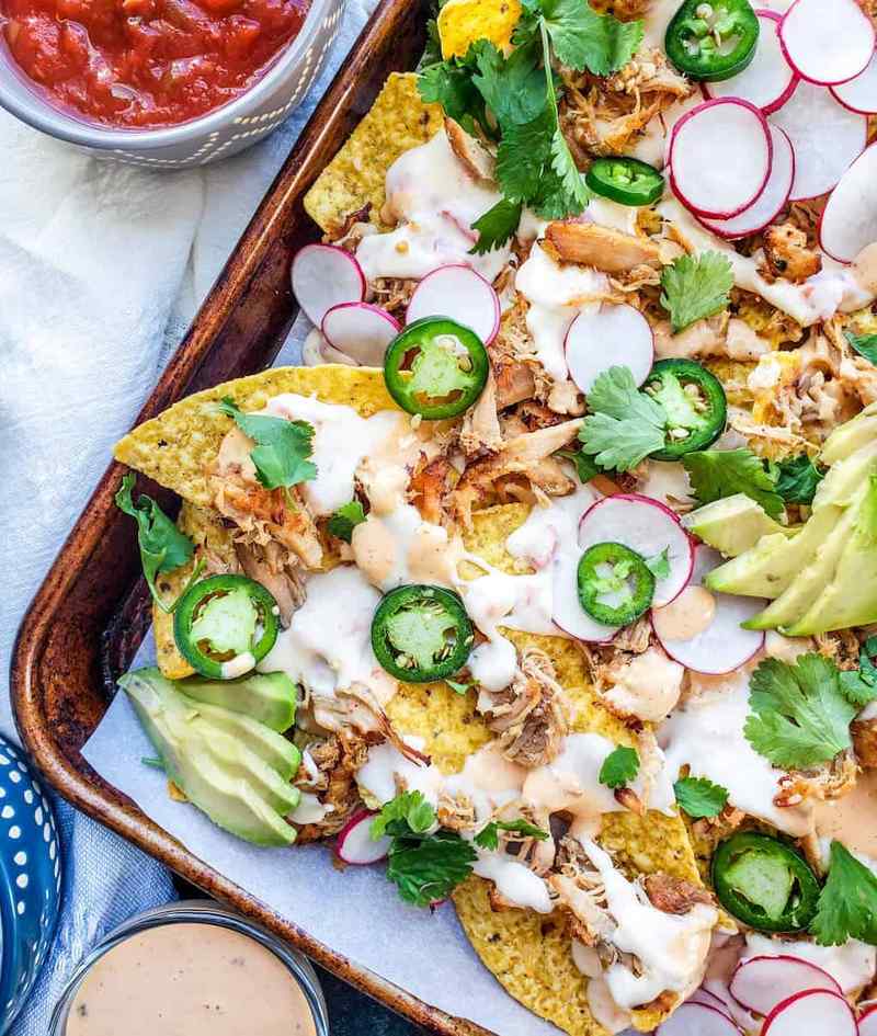 Carnitas pork nachos topped with melted Oaxaca cheese, jalapeños, creamy guacamole, sour cream, and crispy tortilla chips.