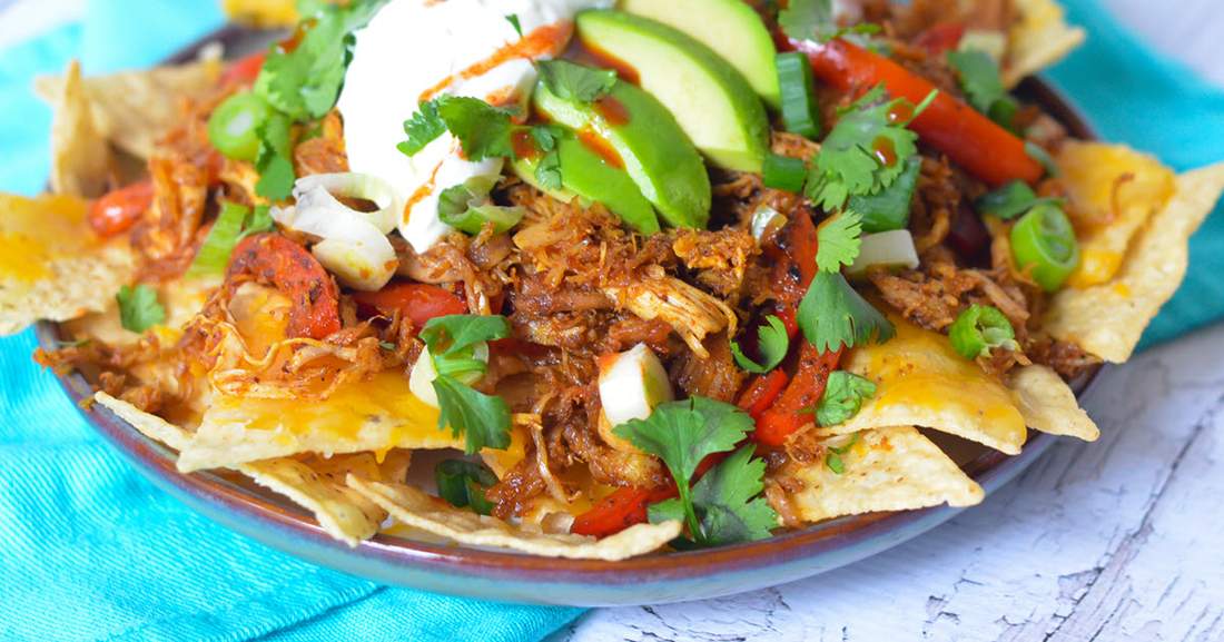 Carnitas pork nachos covered in melted cheese, pickled jalapeños, guacamole, sour cream, and loaded tortilla chips