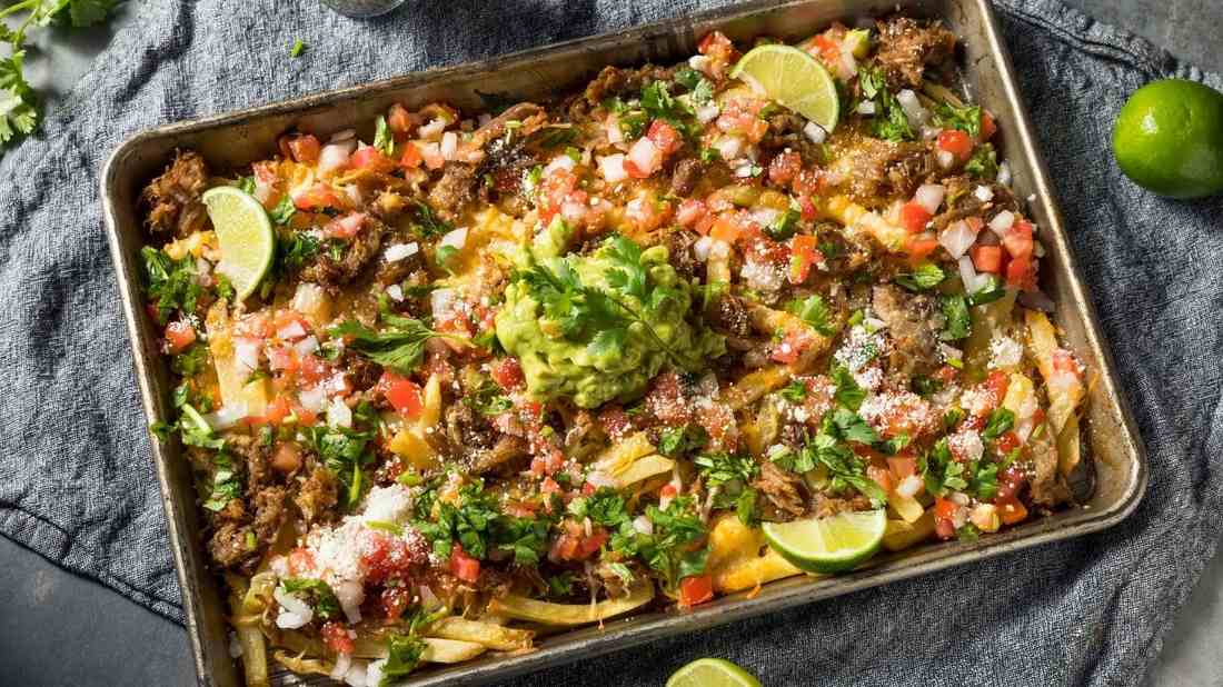 Carnitas pork nachos baked with melted cheese, fresh jalapeños, guacamole, sour cream, and loaded tortilla chips