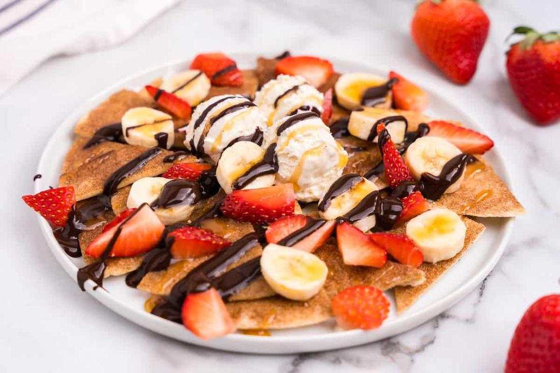 Dessert nachos mimicking melted cheese toppings with sweet jalapeños, guacamole, sour cream, and loaded tortilla chips