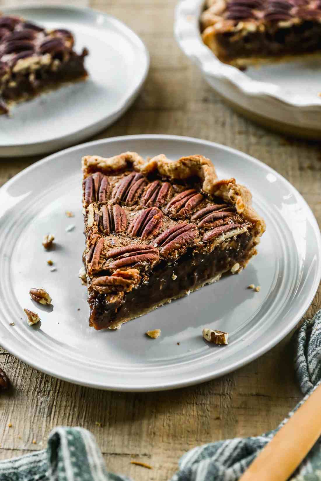 Chocolate pecan pie slice featuring melted bittersweet chocolate pockets and roasted nuts