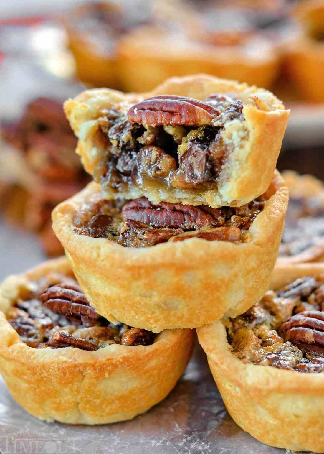 Mini pecan pies in fluted tartlet shells with glossy roasted pecan tops