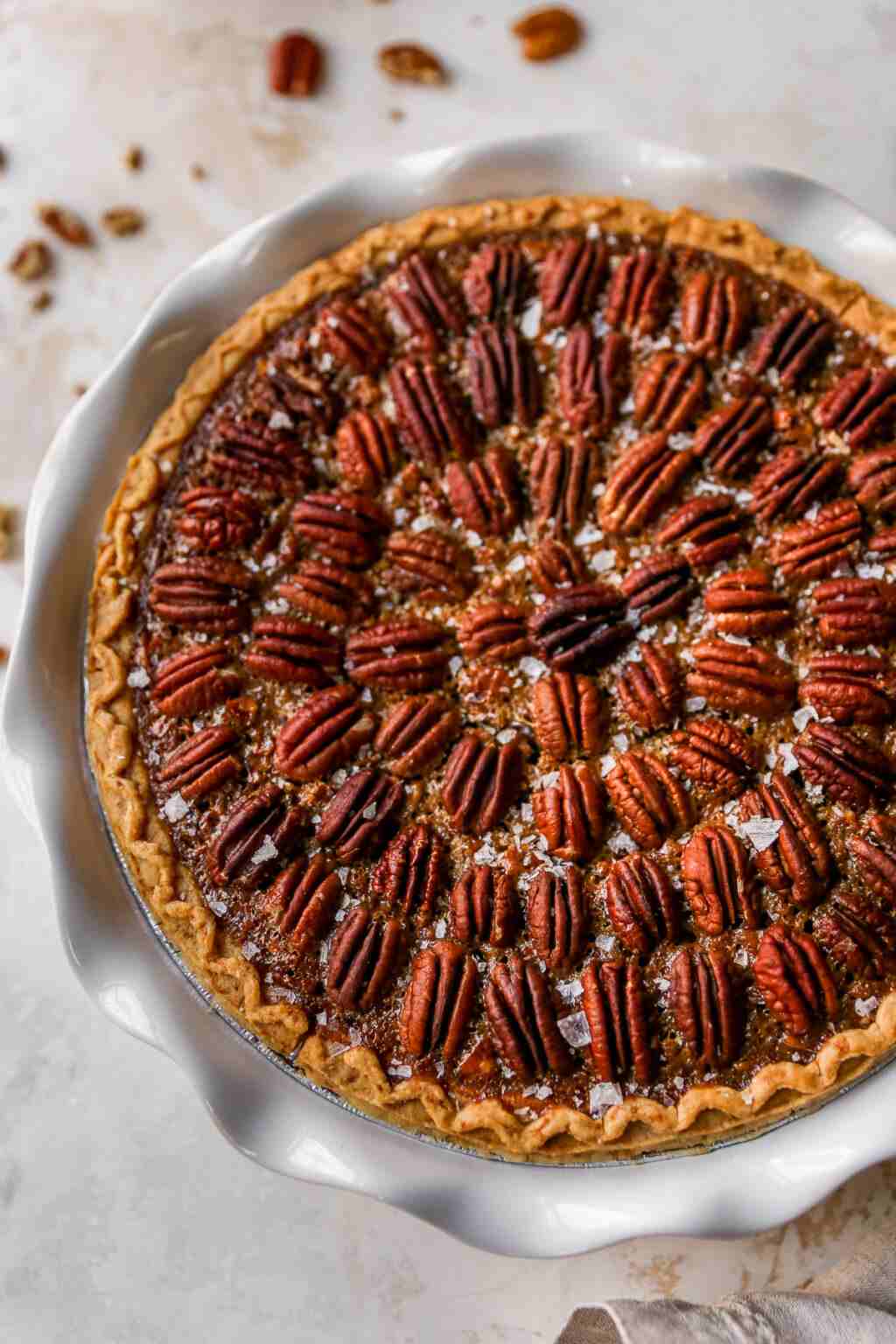 Slice of artisan salted caramel pecan pie showing golden filling and toasted pecans