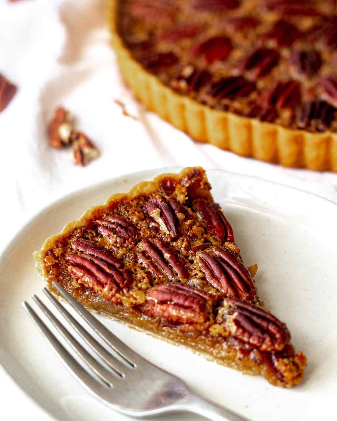 French pastry pecan pie tart slice with golden caramel filling and toasted pecans on crust