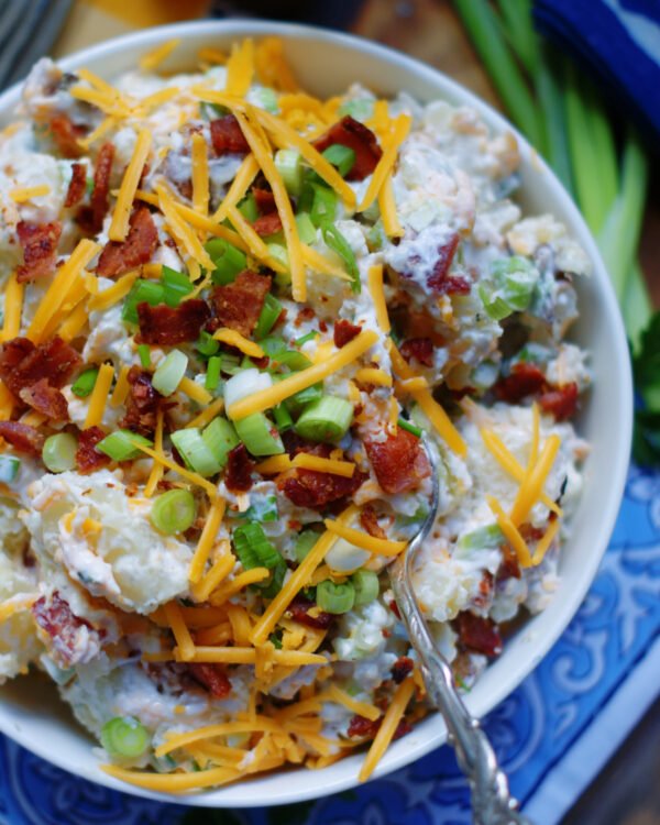 Southern potato salad with hard‑boiled eggs, tangy dressing, celery, and fresh herbs on a bed of fluffy potatoes