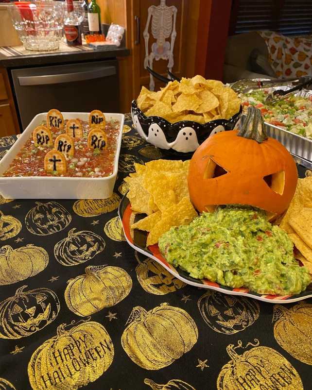 A pumpkin-shaped bowl of guacamole with salsa 