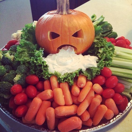 A pumpkin-shaped tray with veggies and ranch dip 
