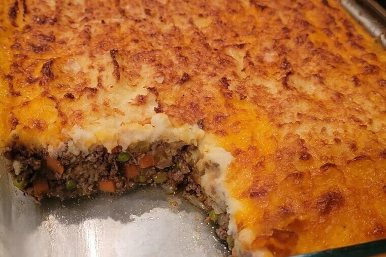 Golden mashed potato crowned homestyle shepherd's pie with savory lamb filling, bubbling cheese, warm casserole