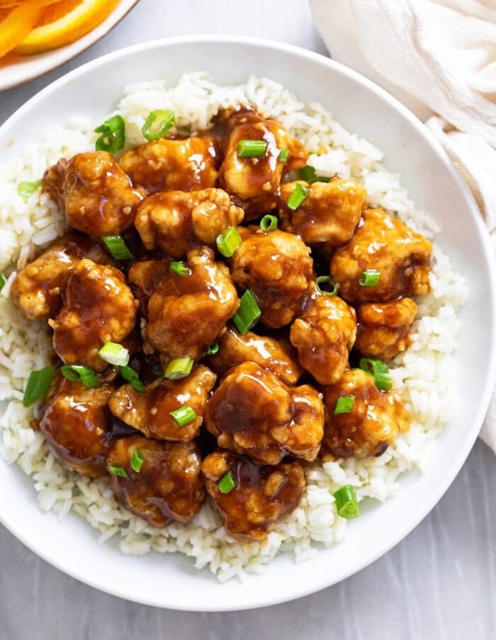 Orange‑glazed chicken served over roasted sweet potato cubes, garnished with fresh orange zest