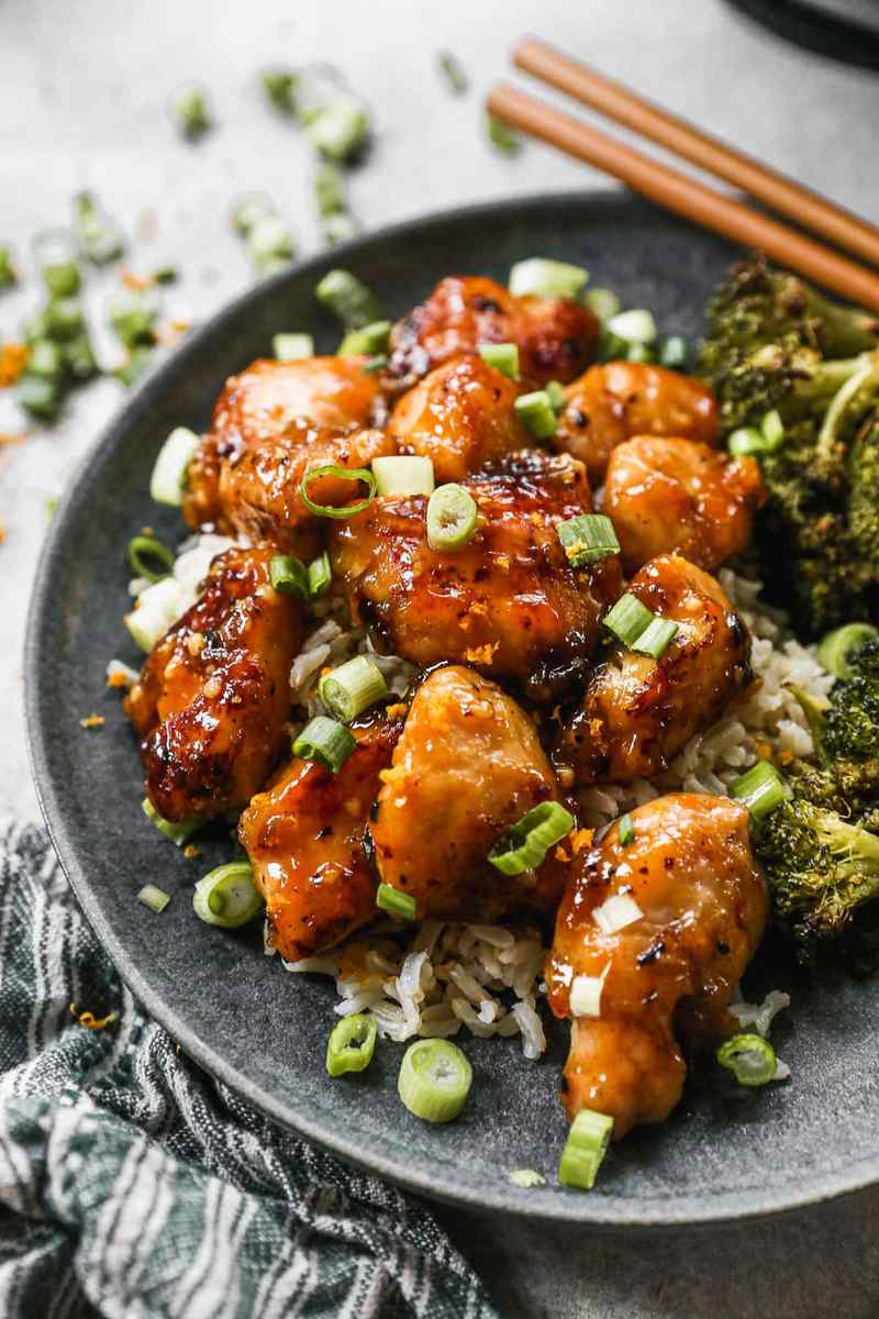 Orange‑glazed chicken topped with lemon zest and fresh garlic, served with a drizzle of orange sauce