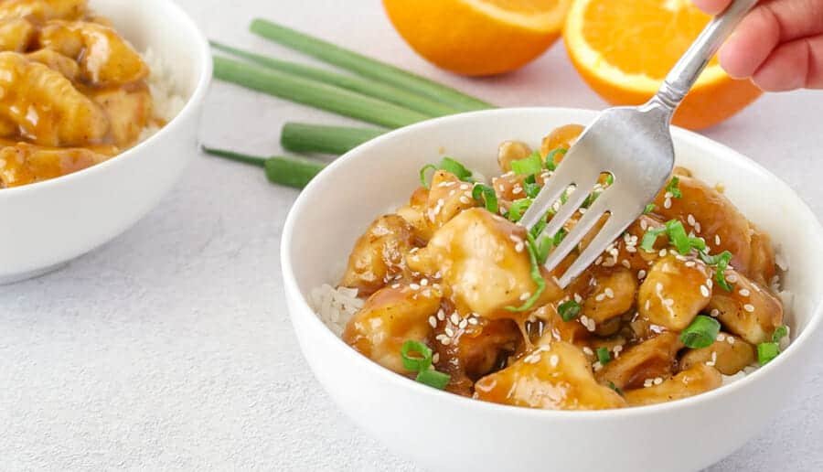 Baked orange‑glazed chicken pieces, golden and crisp, served with a sprinkle of fresh orange zest