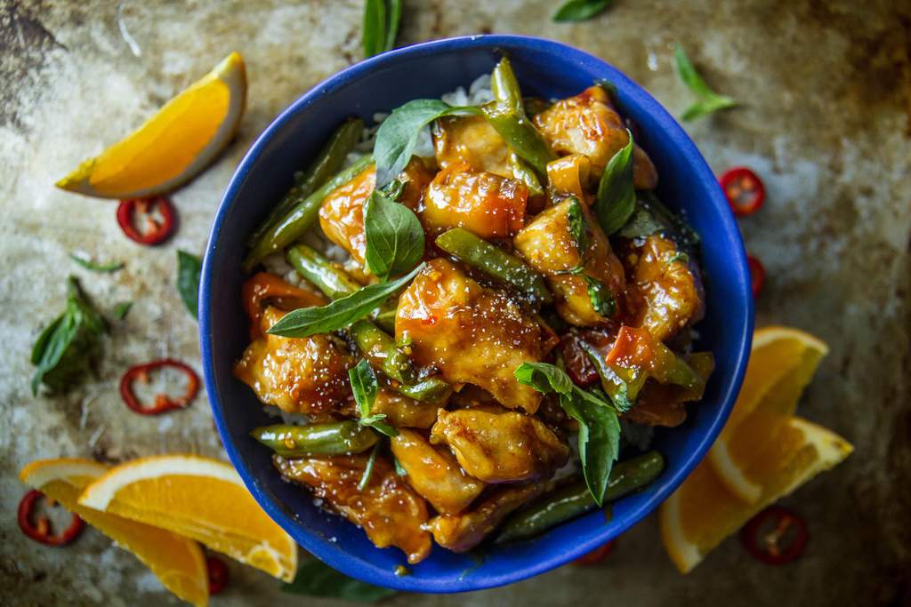 Vibrant orange-glazed skinny chicken served over quinoa with fresh orange segments and cilantro garnish