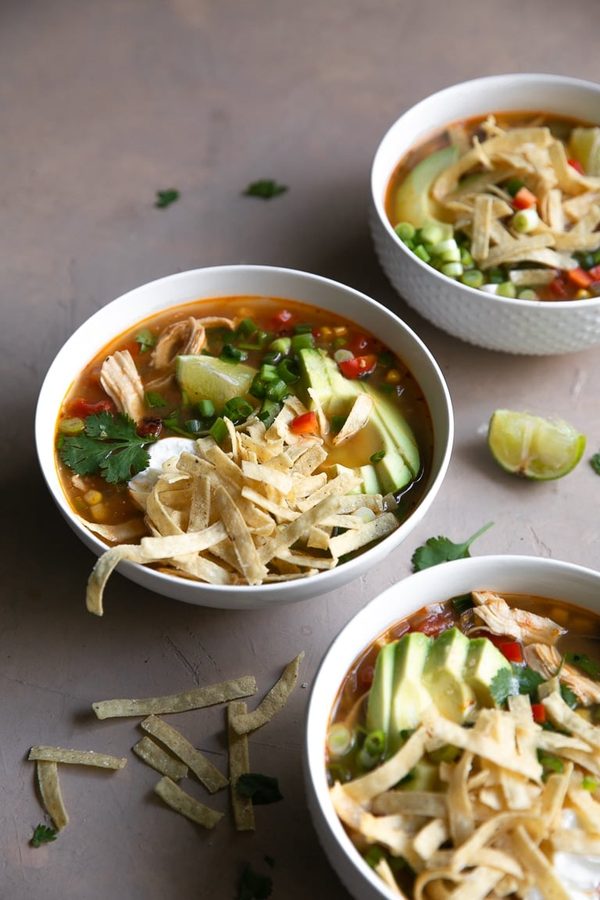 Classic chicken tortilla soup with aromatic broth, shredded chicken, crunchy tortilla strips, avocado, and lime
