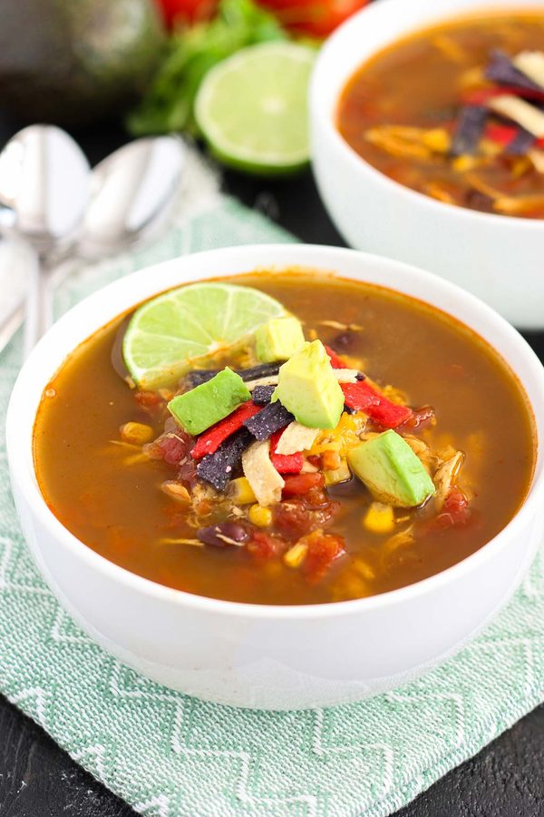 Classic chicken tortilla soup featuring aromatic broth, shredded chicken, crisp tortilla strips, avocado, and lime
