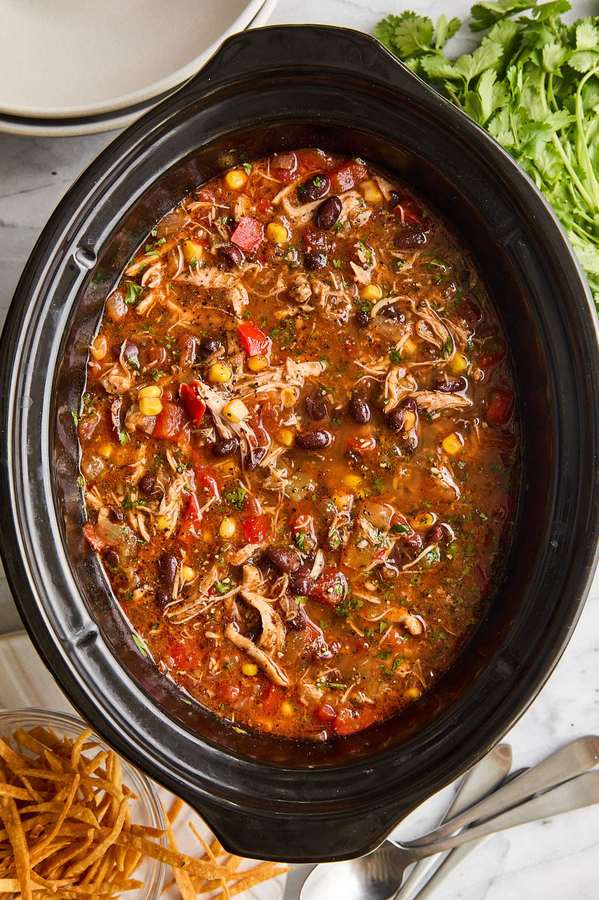 Classic chicken tortilla soup with robust tomato broth, shredded chicken, crispy tortilla strips, avocado, and lime