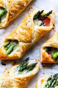 Golden puff pastry bundles filled with asparagus spears and salty prosciutto