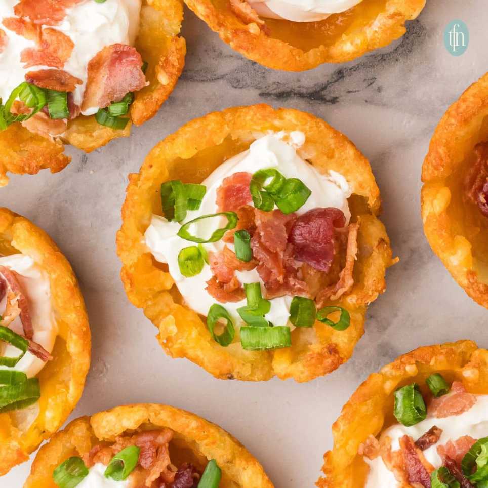 Golden hash brown cups filled with cheddar, bacon, and green onions, baked crisp